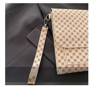 Detail of red geometric floral print on beige leather clutch with wristlet strap