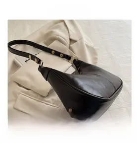 Detail view of dark brown leather hobo bag with gold metal rivets on the shoulder strap