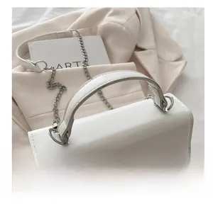 Detail of white PU leather crossbody bag with silver metal bow and fine chain strap