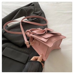 Détail du sac à main en similicuir rose avec grand nœud et poignée au design noué