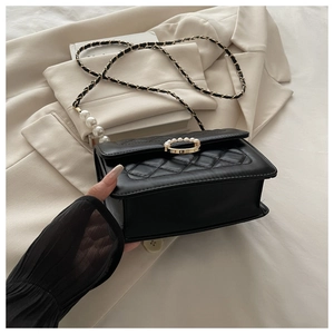 Detail der schwarzen Stepptasche mit goldener Schnalle, Perlen und Kettenriemen