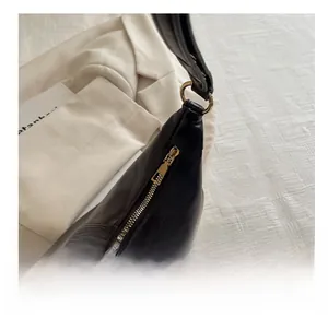 Close-up of smooth gold zipper hardware and leather texture on a black shoulder bag