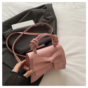 Sac à bandoulière rose avec grand nœud et poignée nouée sur un blazer gris
