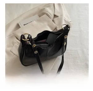 Internal view of black leather underarm bag showing space for phone and wallet with gold rivets