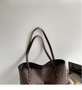 Detail of retro tote bag with M-pattern print, dark brown leather straps, and gold studs