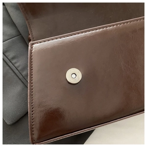 Dettaglio della texture in pelle vintage marrone e chiusura magnetica argentata