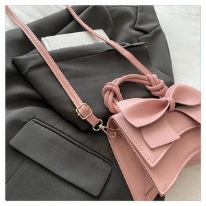Détail du sac rose avec nœud décoratif et poignée nouée sur une veste grise