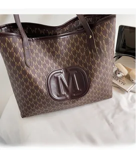 Detailed view of dark brown tote bag featuring M monogram pattern and embossed round logo