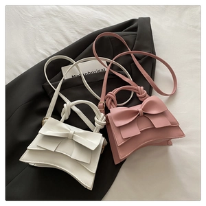 Detail of white and pink bow handbags with twisted handles on a black blazer background