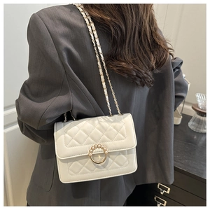Close-up of white quilted leather crossbody bag with pearl circle lock and chain strap