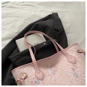 Dettaglio borsa tote rosa in pelle con goffratura geometrica e ricami colorati