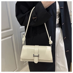 Detail of a creamy white underarm bag with metal square buckle and knot strap detail