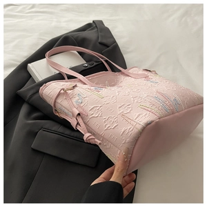 Dettaglio della borsa tote in jacquard rosa con ricami colorati su un blazer nero