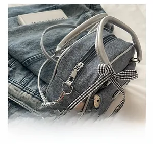 Détails du sac Boston en denim bleu avec poignées argentées et nœud en dentelle