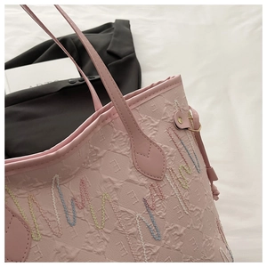 Dettaglio della borsa tote rosa chiaro con ricamo a onde e tessuto in rilievo