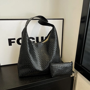 Large black woven leather hobo bag set with matching inner pouch on minimalist table