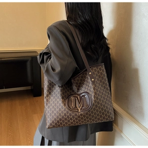 Detail view of large tote bag with vintage letter print and round leather logo patch