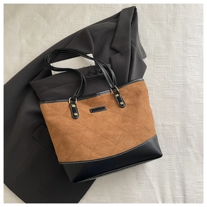 Detail of quilted brown suede tote bag with black leather patchwork and fashion label