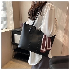 Detail of black tote bag featuring decorative stitching and elegant fashion scarf wrap