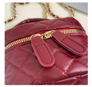 Detailed macro view of the gold double zipper and quilted leather on the burgundy handbag