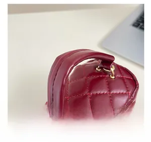 Close-up of wine red quilted handbag handle with gold hardware and fine stitching