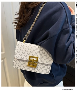 Detailed side view of white crossbody bag with M-pattern and gold chain strap on model
