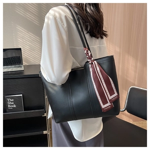 Detail of black PU leather tote bag with a decorative burgundy silk scarf and wide handles