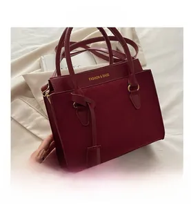 Detail of burgundy crossbody bag featuring faux suede panels and fashion logo print