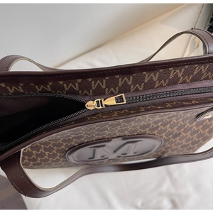 Detailed top view of brown tote bag showing zipper closure and signature M-pattern texture
