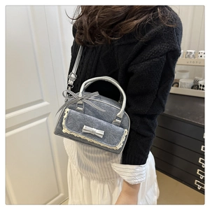 Detail of gray denim handbag featuring white lace trim and silver bow metallic accents