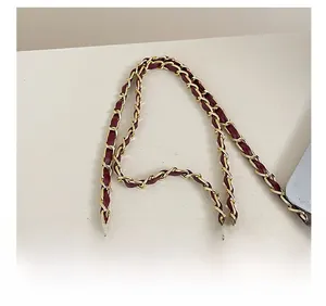 Detail of burgundy leather woven with golden metal chain strap for stylish handbag