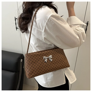 Macro detail of brown shoulder bag with polka dot pattern and silver bow buckle