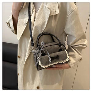 Close-up of retro gray crossbody bag with lace detail and ribbon worn with beige coat