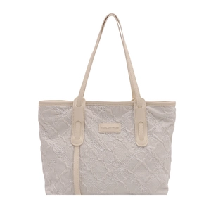 Quilted beige tote bag with white floral embroidery and cream leather handles