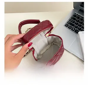 Detailed interior of a burgundy quilted bag with gold zippers and chain strap