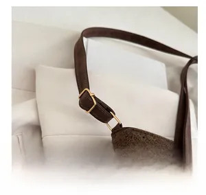 Close-up of golden adjustable buckle on brown crochet tote with leather strap detail