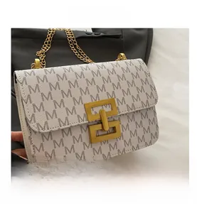 Detail of white crossbody bag with gray M-letter print and large gold metal lock