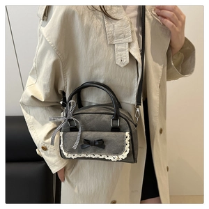 Detail of grey canvas handbag featuring black bow, white lace trim and plaid ribbon accents