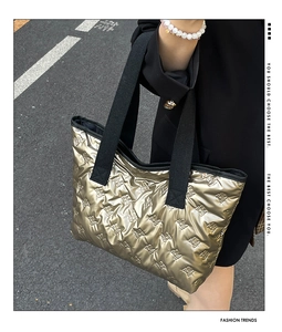 Macro shot of metallic quilted tote bag with embossed patterns and wide black strap
