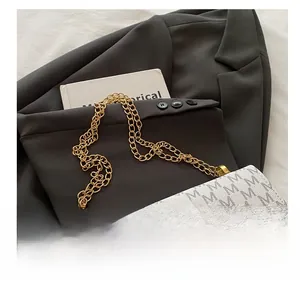 Detail of white crossbody bag featuring monogram M pattern and gold chain strap