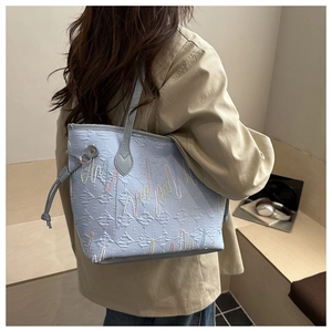 Dettaglio borsa shopper azzurra con lettera E a rilievo e ricamo a onde colorate