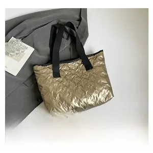 Detail of metallic champagne tote bag with quilted bow pattern and black handles