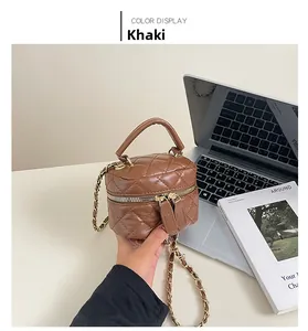 Detailed view of khaki quilted box bag featuring a top handle and gold chain strap