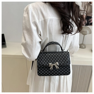 Détail du mini sac à rabat gris avec nœud en argent et bandoulière en chaîne