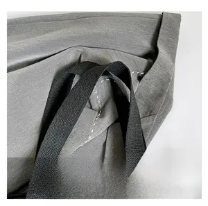 Close-up of durable nylon handles and reinforced white stitching on a gray tote bag