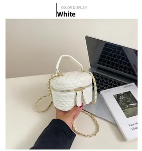 Detail of white quilted mini bucket bag with gold-tone chain strap and dual zippers