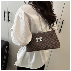 Detail of coffee brown shoulder bag featuring M-letter print and silver bow buckle