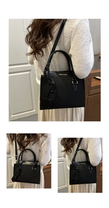 Detail of black matte shoulder bag with gold text and adjustable strap on a model