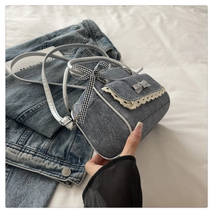 Detail of blue denim crossbody bag with lace trim and checkered bow in retro style