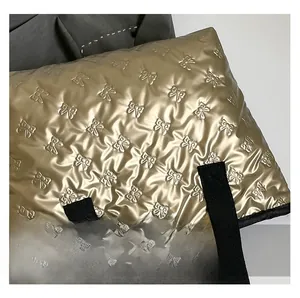 Close-up of champagne gold tote bag with quilted bow texture and glossy metallic finish